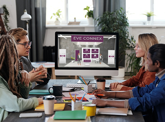 Blog | Konferenzraum mit vier Personen verfolgen virtuellen Messestand gemeinsam am PC