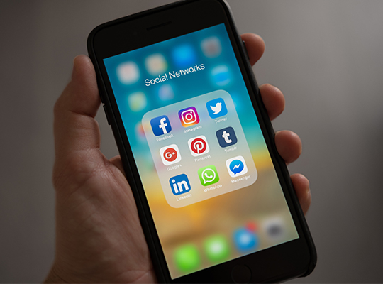 Blog | Hand hält ein Smartphone mit verschiedenen Social Media Apps